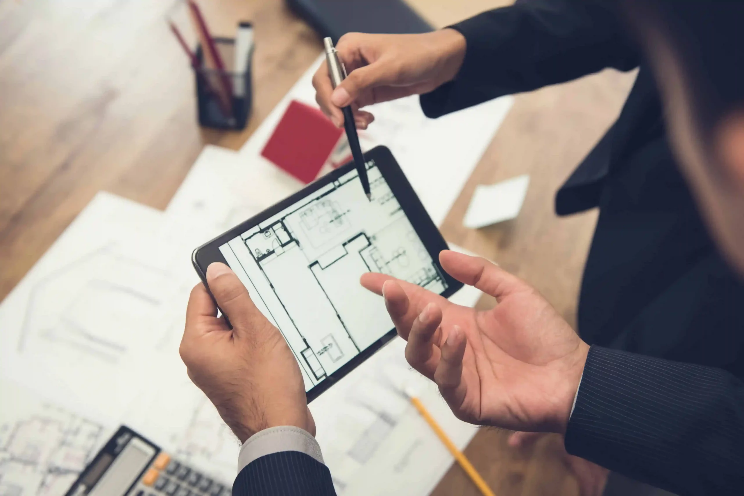 Zwei Experten analysieren einen Grundriss auf einem Tablet für ein Immobiliengutachten